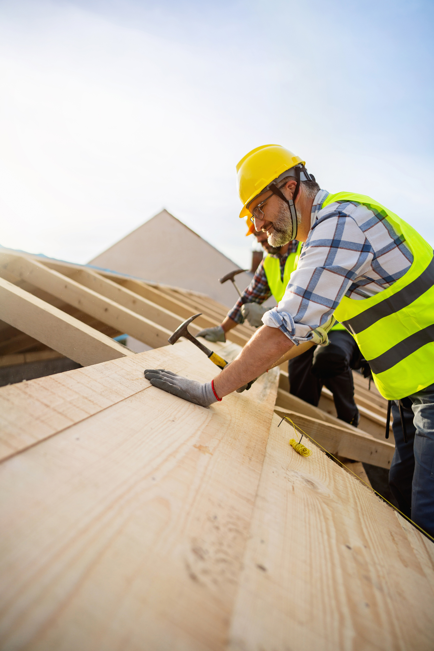 Roofing contractor inspecting damaged shingles on a Maine roof